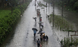 People walk on flooded railway tracks during heavy rains in Mumbai, India on 04 September...