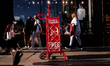 People walk past a trolley full of the day's London Evening Standard on Oxford Street Lond...