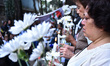  Relatives of the victims holds white flowers during a mass by people who lost their lives...