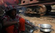A homeless women in cooking infron her temporary house beside a rail line at Dhaka, Bangla...