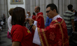 A priest gives a communion wafer to a faithful woman during a Good Friday ceremony in fron...