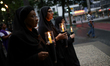 Religious women carry candles during a Good Friday ceremony in front of the Sé Cathedral i...