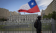 A demonstrator waves a Chilean national flag poked with holes in front the Moneda Palace...