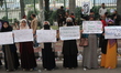 Students and local residents hold placards and raise slogans as they take part in a protes...