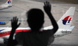 A young child looks at the Malaysia Airline's fleet taxi on the tarmac as it enters the ni...