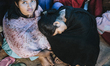 A group of women take shelter from the rain beneath a tarpaulin after their homes were des...