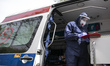 Medical worker wearing protective suit, verifying patient's medical files in an ambulance...