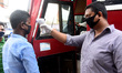 Worker examines the body temperature of passengers before entering the bus as they travel...