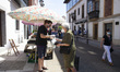 An older woman buys vegetables from a small farmer at the weekly market in Norenia, , in N...