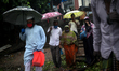 People hold umbrella as they ride on a boat to cross the river Buriganga during rain near...