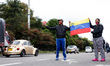 A Venezuelan family is waving their country flag to cars passing by asking for any kind of...