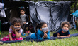 Venezuelan children are hanging out in front of their tent in the makeshift migrant camp a...