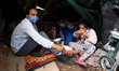 A mother and daughter sat in their tent having some of the food that was donated to the th...