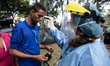 A Venezuelan migrant getting his temperature checked by health worker in the makeshift mig...