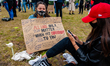 Two white girls are sitting while holding a placard, during the second massive Black Lives...
