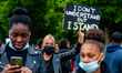 A white woman is holding an anti racist placard between two black women, during the second...