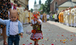 A young girl wearing traditional folk dress scatters flower petals along the Corpus Christ...
