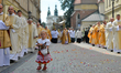A young girl wearing traditional folk dress scatters flower petals along the Corpus Christ...