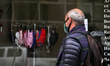 A man looks in the stained glass window at the chinstrap sold in a local clothing store on...