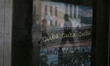 Pedestrians are reflected on a  movie poster in a window across from the Capatolio Naciona...