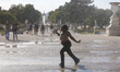 Tourists refresh themselves with water at the "Jardin des Tuileries" during a warm afterno...