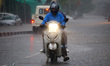 Indian People drives through a flooded road during a Heavy Monsoon Rain shower in Ajmer, R...