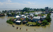 People walking through a submerged road beside the Padma river as the flood situation wors...