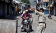 A policeman stops a bike rider after Strict lockdown re-imposed in Baramulla due to spike...