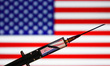 In this illustration photo medical syringe is seen with American flag in the background. P...