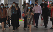 People wearing face masks walk past a Chong Nonsi skywalk in Bangkok's central of business...