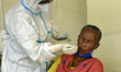 A health worker in personal protective equipment (PPE) collects a nasal swab samples from...