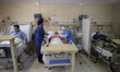 Iranian medical personnel wearing protective suits take care of an elderly man who has inf...