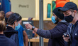 A view of a person having a temperature check before being allowed in to an Apple Store in...