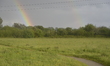 Sunlight refracting in rainwater to create a double rainbow, arching over power lines in S...