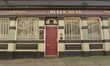A traditional public house, commonly known as a pub, refecting light and the scene opposit...
