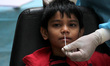 A health worker collects a nasal swab sample from residing children at recovery shelter, f...