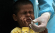 A health worker collects a nasal swab sample from residing children at recovery shelter, f...