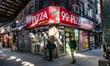 A man passing in front of 99c dolar slice pizza holding his phone and walking. Daily life...