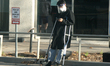 Man on crutches wearing a plastic face shield and face mask as he waits outside North York...
