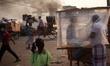 A cake vendor waits for customer inside his polythene wrapped shop as passerby make their...