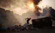A labour works at a garbage area as fire creates toxic smoke at Keraniganj area in Dhaka,...