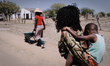 Felicia carries her son while her mother fetch water from the well of the family village n...