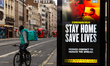A delivery man on his bicycle is seen riding by the NHS 'Stay Home' poster as the UK's gov...