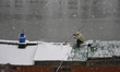 A man clears the roof of a houseboat amid heavy snowfall in Srinagar, Indian Administered...