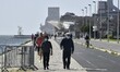People wearing protective masks walk along Docas Da Ponte boulevard, Lisbon. 24 February 2...
