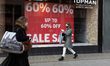 Women in protective face masks walk in front of closed Topman show on Oxford Street during...