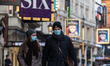 A couple in Protective face masks walk  on usually very busy Shaftesbury Avenue in West En...