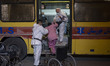 An Iranian female medical personnel and a health assistant wearing protective suits help a...