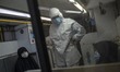 A health assistant wearing a protective suit speaks with two veiled women who have infecte...