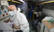 A medical personnel wearing a protective suit looks on as a man who has infected by the CO...